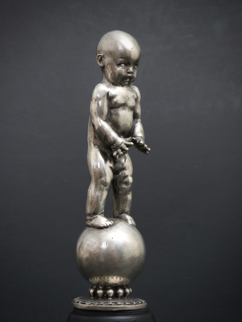 En vente :  MASCOTTE BEBE A LA BOULE OU A L'EQUILIBRE BRONZE PATINE ARGENT